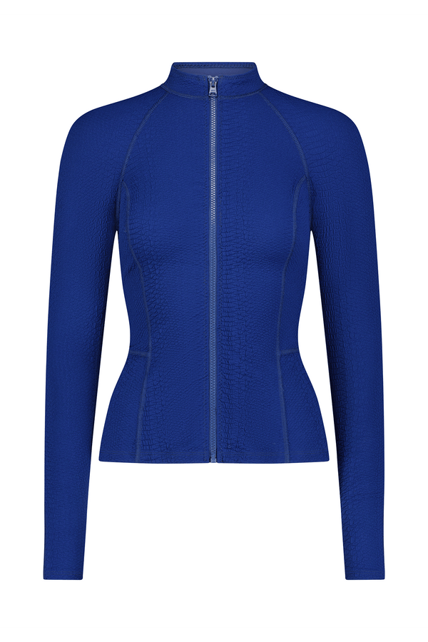 The Natasha Jacket by Gigi C Sport features a blue long-sleeved, fitted design with textured fabric. It includes seam detailing, a high collar, and a full-length zipper for a tailored look, making it essential for your wardrobe.