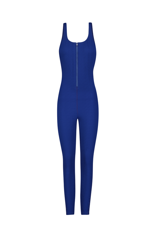 The Merit Jumpsuit by Gigi C Sport is a blue sleeveless piece made from bi-stretch compression fabric, showcasing a faux snake jacquard pattern, fitted design, and front zipper closure.