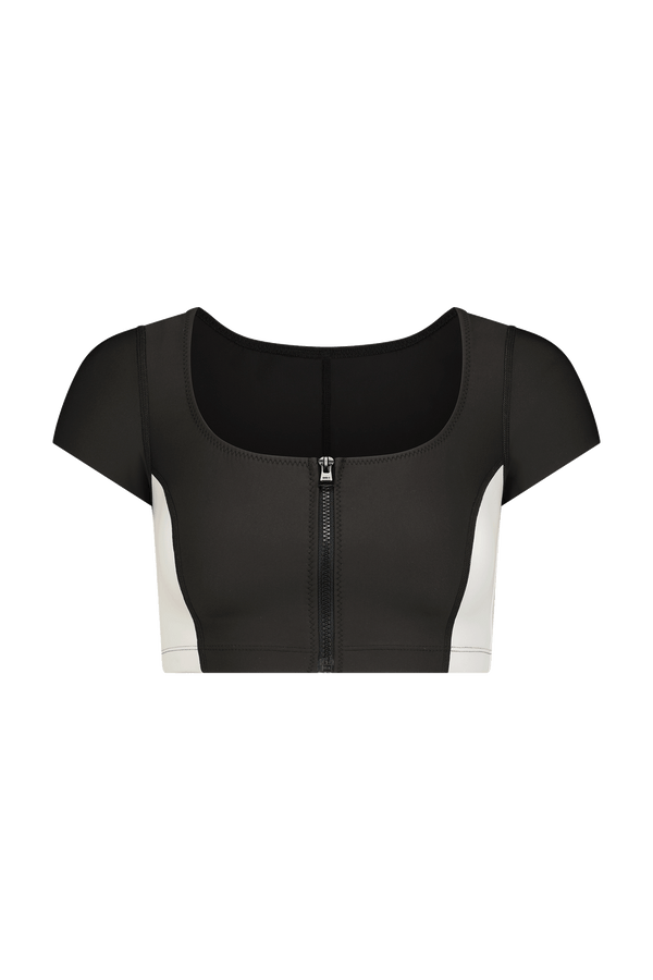 Introducing the Maci Crop Top by Gigi C Bikinis: a versatile athletic-style piece featuring a decorative front zipper, short sleeves, and a scoop neckline in black and white fashion scuba fabric, striking against the plain white backdrop.