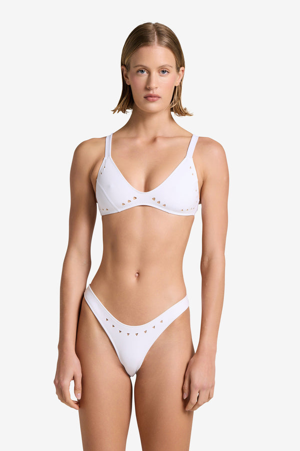 Person wearing the Georgia Top by Gigi C Bikinis, a white bikini featuring laser cut detailing, standing against a plain background.