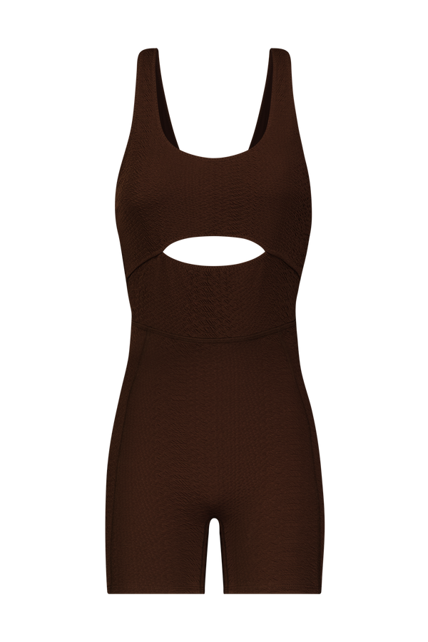 The Sawyer Romper by Gigi C Sport is a brown, sleeveless romper featuring a faux snake fabric with a midriff peek-a-boo front cutout and fitted shorts.