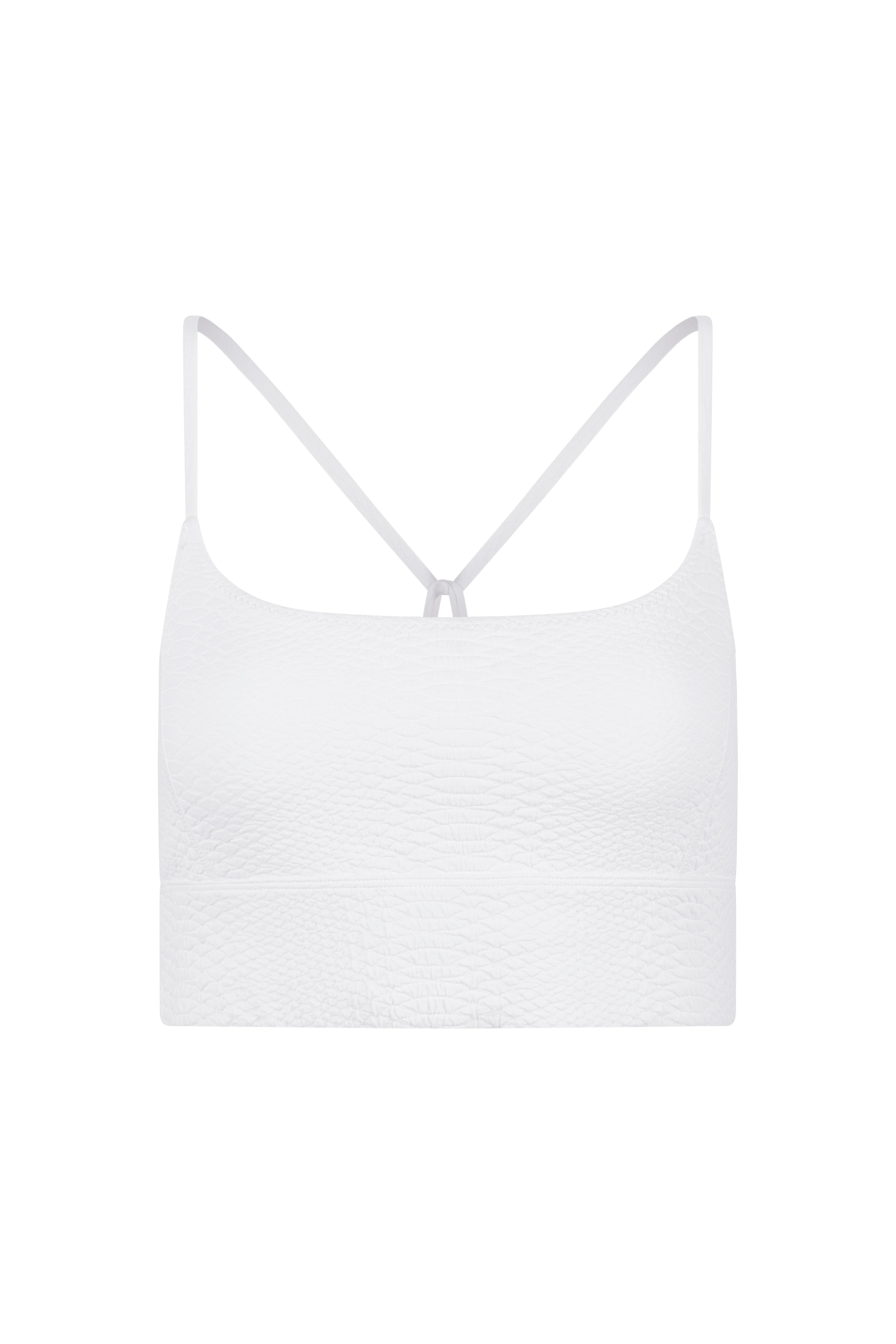 The Finle Bra by Gigi C Sport is a white cropped tank top featuring thin straps and a subtle textured pattern, made from snakeskin-embossed fabric, displayed on a plain white background.