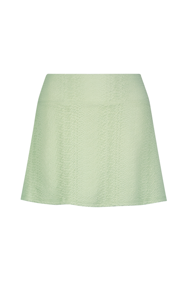 The Heidi Skirt by Gigi C Sport is a mini design featuring light green texture on a black backdrop. Made from bi-stretch compression waffle jacquard fabric, it offers an A-line shape, fitted waist, and subtle vertical seams.