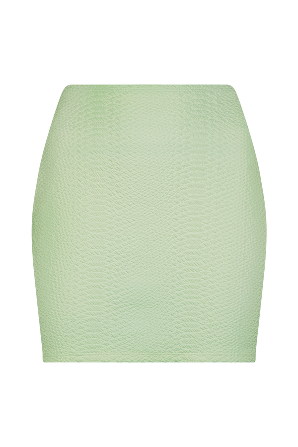 Introducing the Joelle Skirt by Gigi C Bikinis: a light green, high-waisted skirt made from luxurious waffle jacquard. Its textured, fitted silhouette pops against a simple black backdrop.
