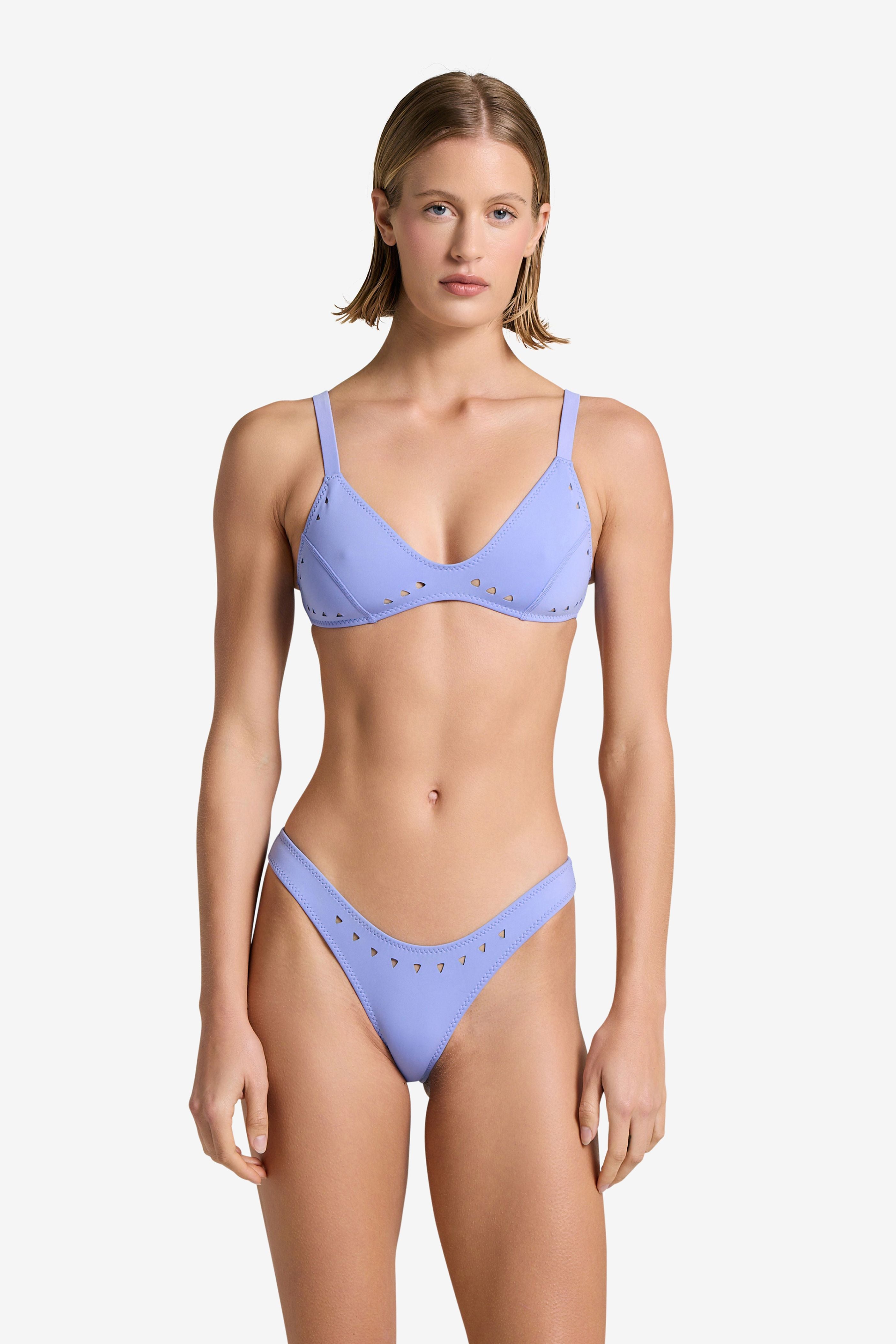 A woman with short, wet hair confidently poses in the Georgia Top by Gigi C Bikinis, a light purple bikini featuring laser cut detailing. She stands against a plain white background, looking directly at the camera.