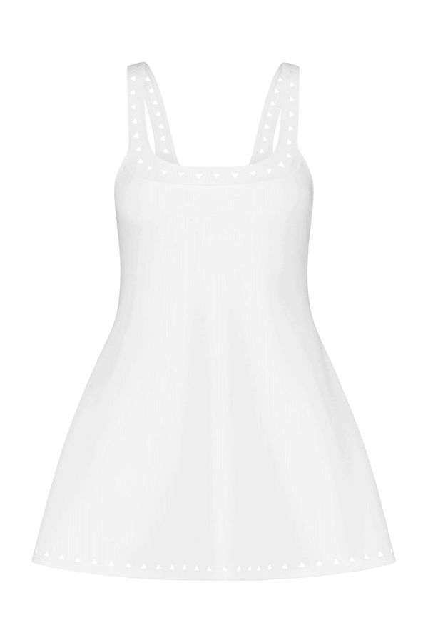 The Avery Dress by Gigi C Sport is a white sleeveless piece with thin straps, featuring elegant heart-shaped laser cutouts along the neckline and hem. Its lightweight fabric and flared skirt provide a flowy appearance.