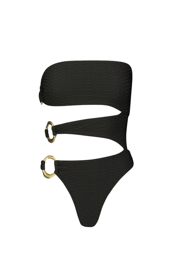 The Sami One Piece by Gigi C Bikinis is a stylish black swimsuit with asymmetric rings and cut-outs, adorned with two gold accents on the sides. It features textured fabric for a luxurious feel and skimpy bottom coverage for a daring look.