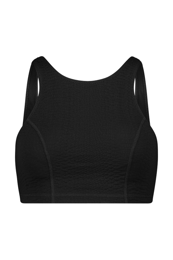 The Devon Top by Gigi C Sport is a black textured sports crop with wide straps and a scoop neck, offering medium support through bi-stretch compression. Its faux snake design on a white background adds exotic flair, while the fabric remains slightly stretchy and fitted for athletic use.