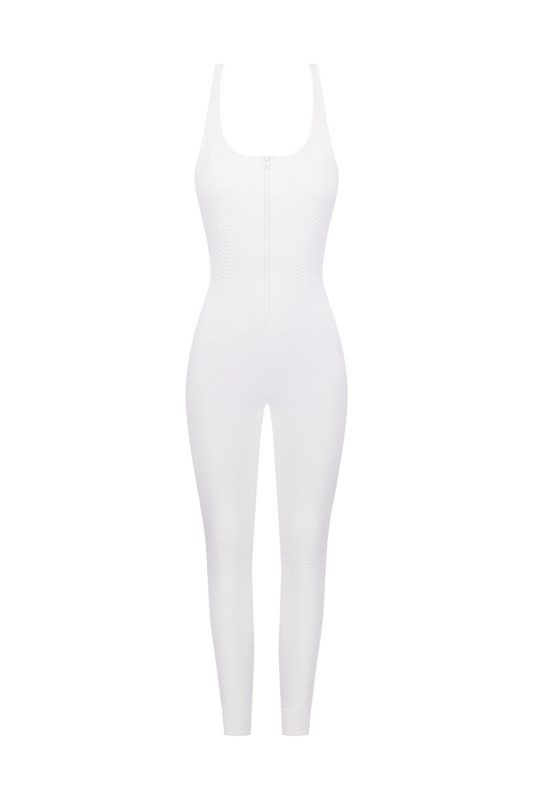 The Merit Jumpsuit by Gigi C Sport is a white, form-fitting piece featuring a halter neck and front zipper, set against a black background. Its sleek, athletic design includes multidimensional stretch with textured faux snake jacquard for an edgy touch.