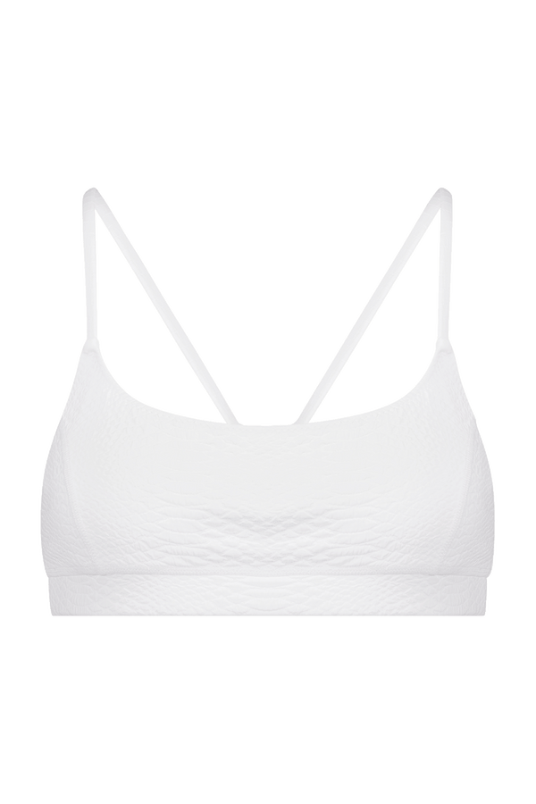 Discover the Gigi C Sport Emery Bra: a white bralette with a textured pattern, thin double straps with loop detail, and breathable knit construction against a black backdrop for ultimate comfort and style.