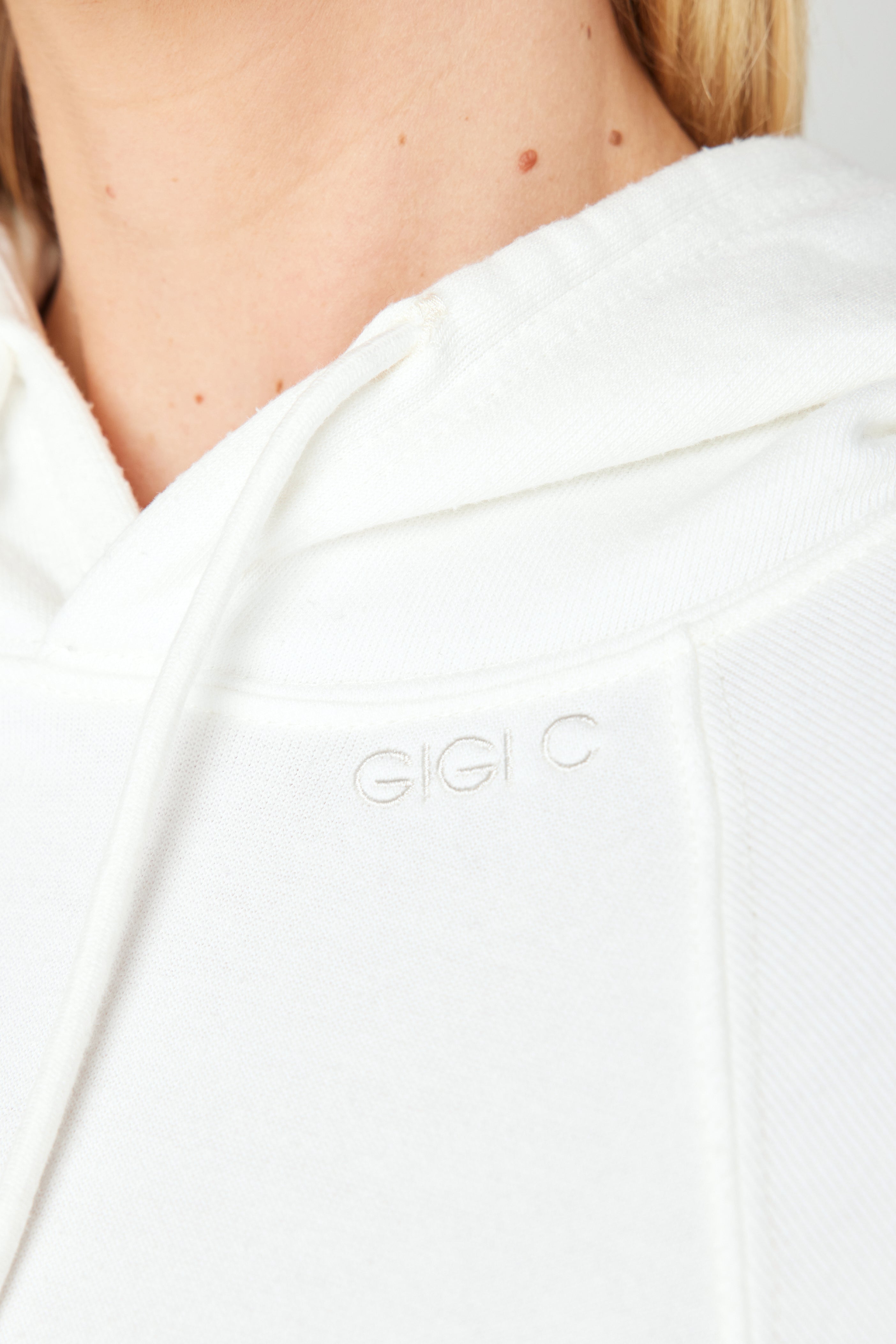 A cropped Juliet Hoodie from Gigi C Lounge is worn by someone, showcasing GIGI C subtly embroidered on the chest. The loop terry fleece fabric looks soft and textured, while the persons face remains unseen.